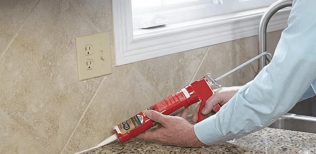Handyman applying caulk along a kitchen backsplash and countertop seam in Fort Lauderdale, FL