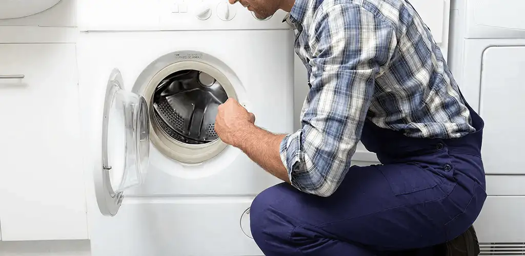 Handyman inspecting a dryer drum and internal parts for repair in Fort Lauderdale, FL