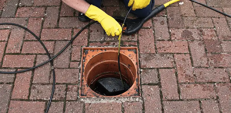 Drain cleaning technician using a drain snake to clear a clogged drain in Fort Lauderdale, FL
