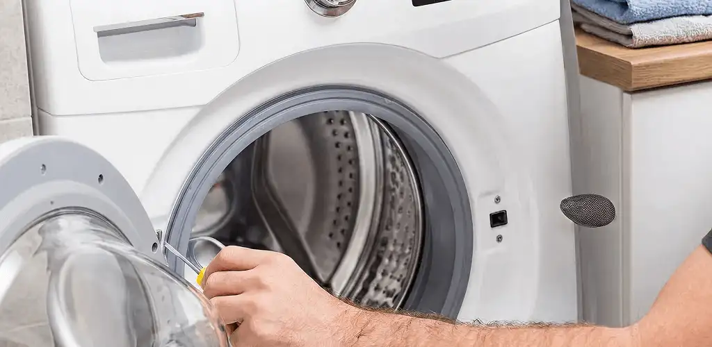 Handyman repairing a front-load washing machine and inspecting the drum in Fort Lauderdale, FL